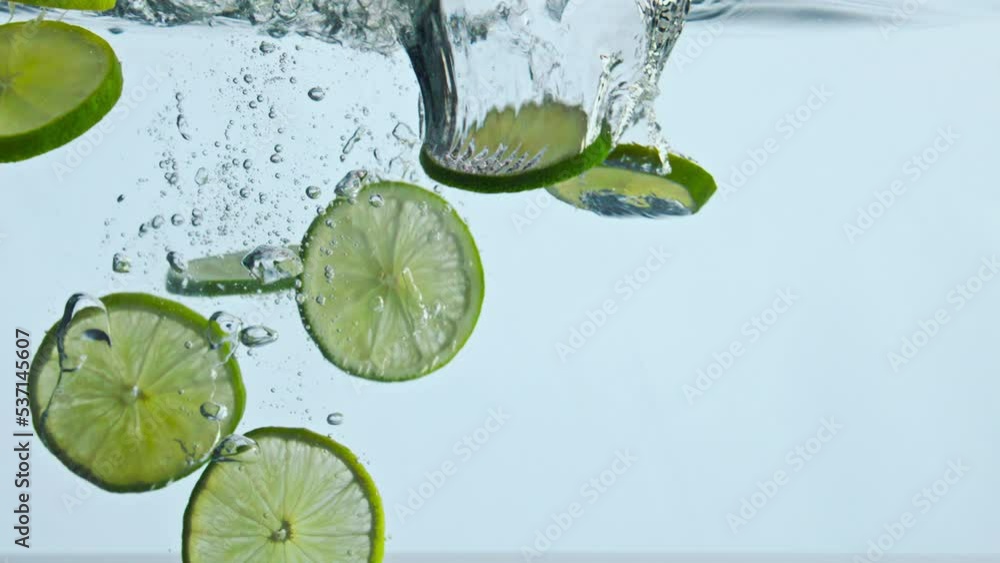 Closeup lime slices underwater on white background. Citrus falling under water. Closeup lime slices underwater on white background. Citrus falling under water.