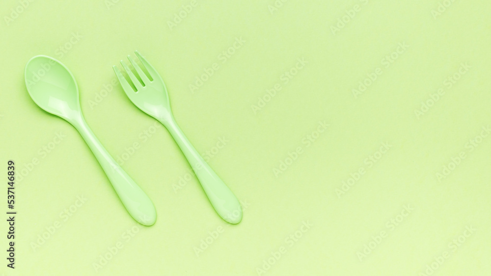 Green fork and spoon on a green background. A place for your text. Flat lay. Green fork and spoon on a green background. A place for your text. Flat lay.
