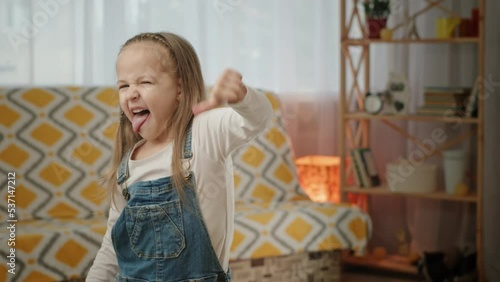 Schoolgirl shows thumb down sticking out tongue in disgust photo