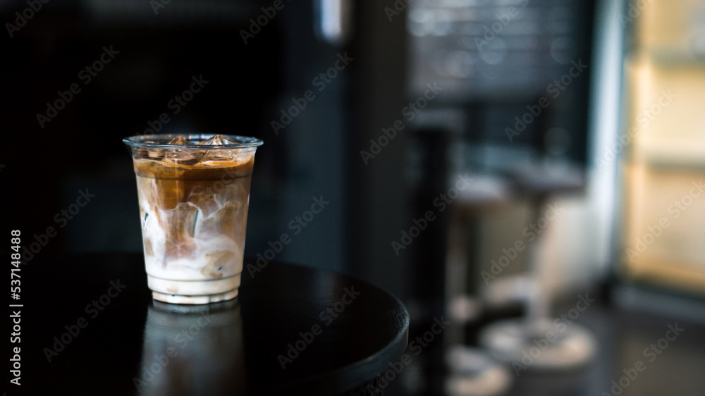 Ice coffee on a plastic cup with cream being poured into it showing the texture Ice coffee on a plastic cup with cream being poured into it showing the texture