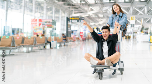 Happy smiling asian male and female waiting for flight and Check-in by mobile phone in terminal background.asian couple are traveling after the coronavirus 2019 (COVID-19) outbreak ends.