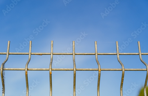 close up of metal fence on blue sky background