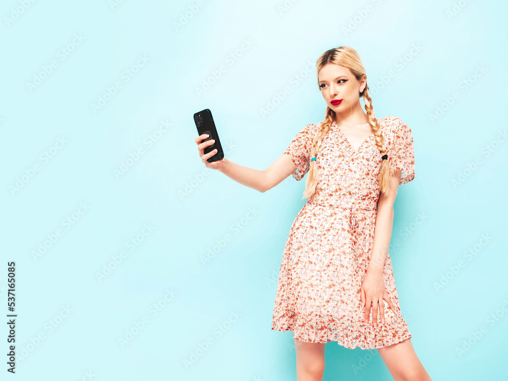 Young beautiful smiling female in trendy summer dress. Sexy carefree blond woman posing near wall in studio. Positive model having fun. Cheerful and happy. Takes selfie Young beautiful smiling female in trendy summer dress. Sexy carefree blond woman posing near wall in studio. Positive model having fun. Cheerful and happy. Takes selfie