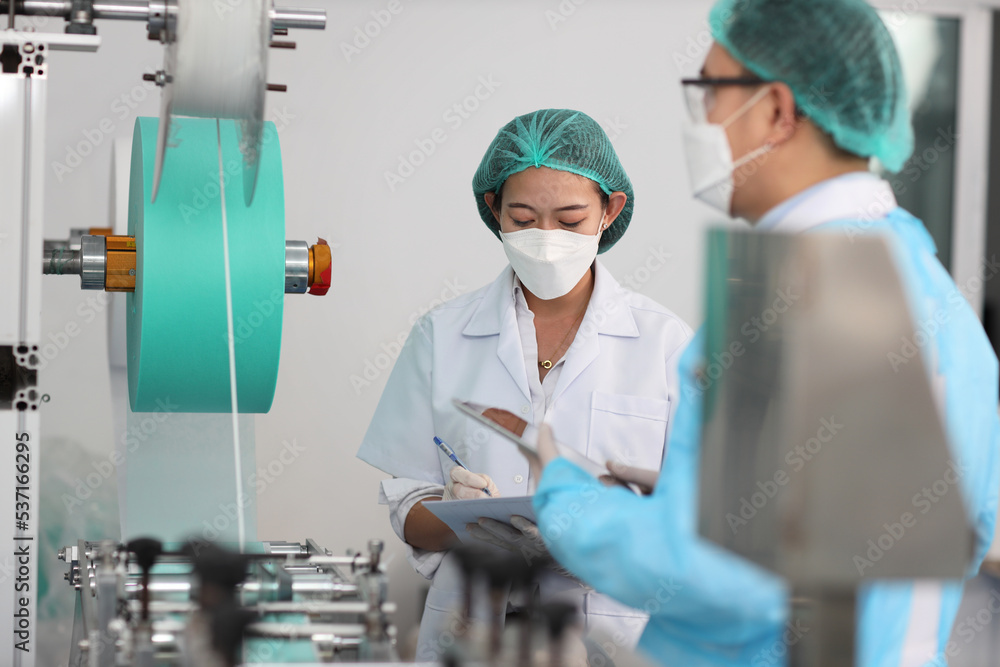 Inspector woman and colleague man working on quality of mask and medical face mask production line, Industry and factory concept. Inspector woman and colleague man working on quality of mask and medical face mask production line, Industry and factory concept.