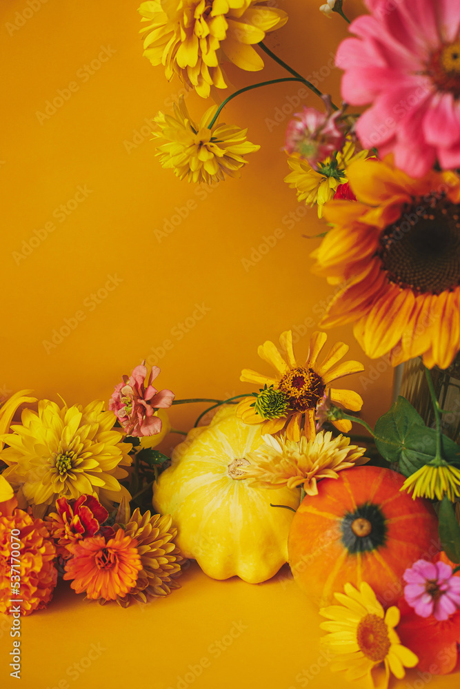 Stylish autumn composition. Colorful flowers, pumpkin, pattypan squash on yellow background. Creative modern autumnal still life. Seasons greeting card template with space for text. Hello Fall