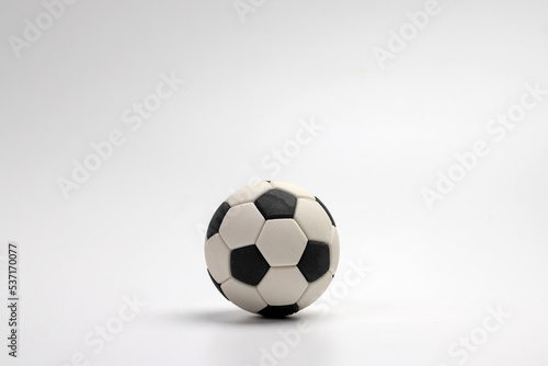 miniature toy football soccer ball black and white over white background copy text space concept