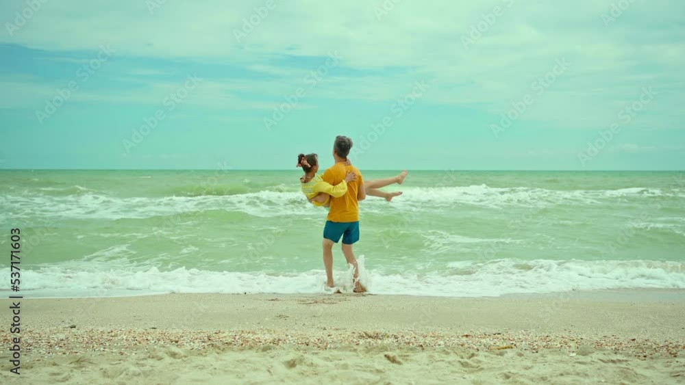 A happy positive smiling young couple in love man and woman are walking sandy beach close to waving sea, hugging and kissing in summer. man takes girl on hands and circling A happy positive smiling young couple in love man and woman are walking sandy beach close to waving sea, hugging and kissing in summer. man takes girl on hands and circling