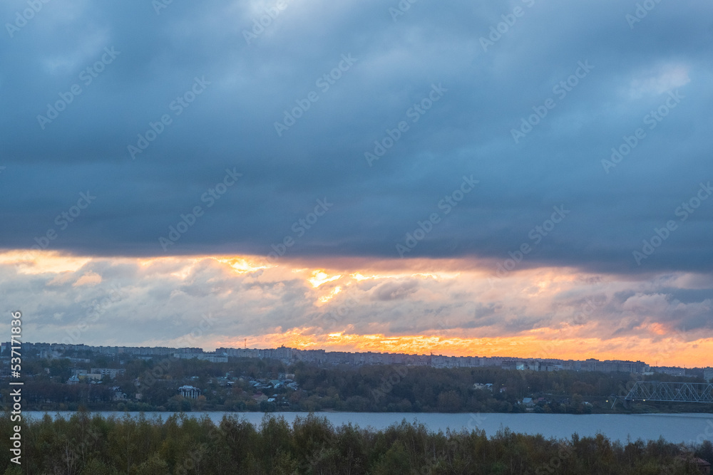 Sunrise over the city across the river. Panoramic View. Colorful sky with sun in clouds.