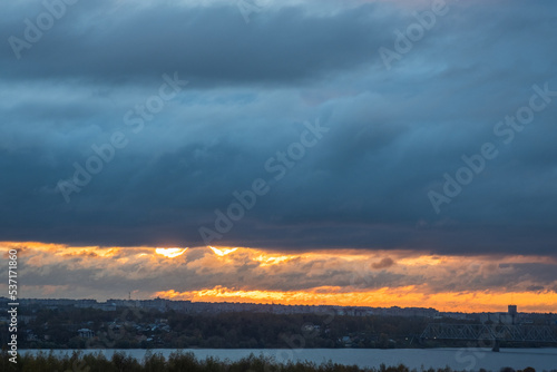 Sunrise over the city across the river. Panoramic View. Colorful sky with sun in clouds.