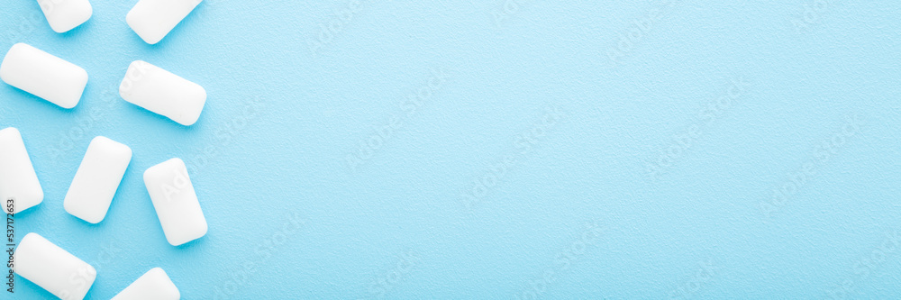 White chewing gum pads on light blue table background. Pastel color. Closeup. Wide banner. Empty place for text. Top down view. White chewing gum pads on light blue table background. Pastel color. Closeup. Wide banner. Empty place for text. Top down view.