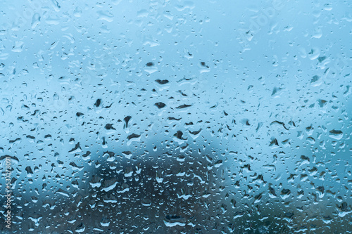 Water drops on window glass. Raindrops on window. Blue tone. Natural water drop texture