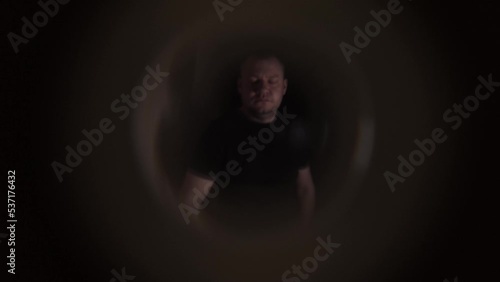 A disgruntled angry neighbor stands on the stairwell and knocks on the door of the apartment. View from the peephole. Close-up
