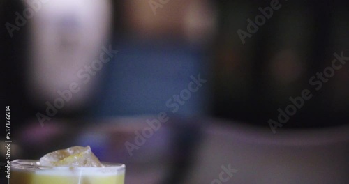 Amazing close-up of a bartender's shaker container pouring a drink into a glass with ice to present their preparation. photo
