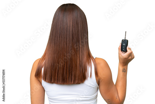 Young caucasian woman holding car keys isolated on green chroma background background in back position