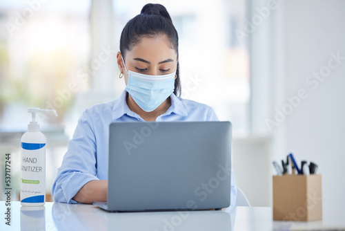 Business woman with laptop, during covid with mask and hand sanitizer for hygiene and health. Young corporate professional, safety and sanitation while working in office during pandemic.