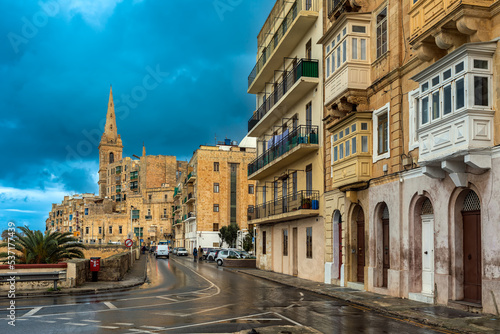 Traditional buildings and church under cloudy sky in Valletta, Malta.