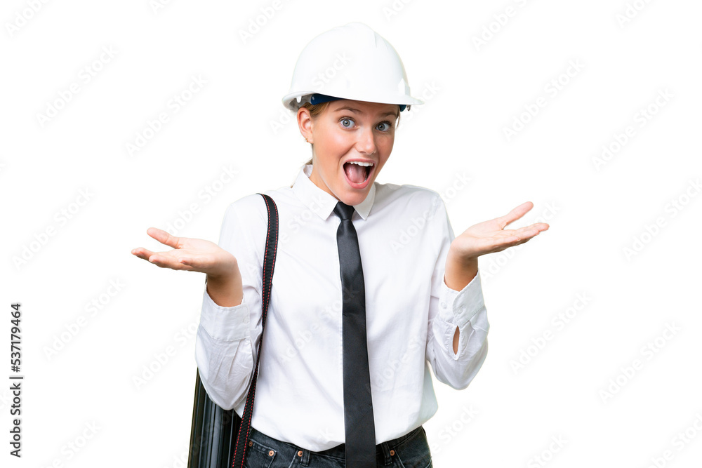 Young architect caucasian woman with helmet and holding blueprints over isolated background with shocked facial expression