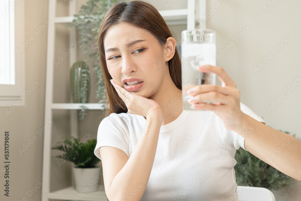 Suffering from toothache, asian young woman, girl touch cheek, face expression ache or feel pain, sensitive molar teeth, hand holding glass of water with ice, inflammation when drink cold, healthcare. Suffering from toothache, asian young woman, girl touch cheek, face expression ache or feel pain, sensitive molar teeth, hand holding glass of water with ice, inflammation when drink cold, healthcare.