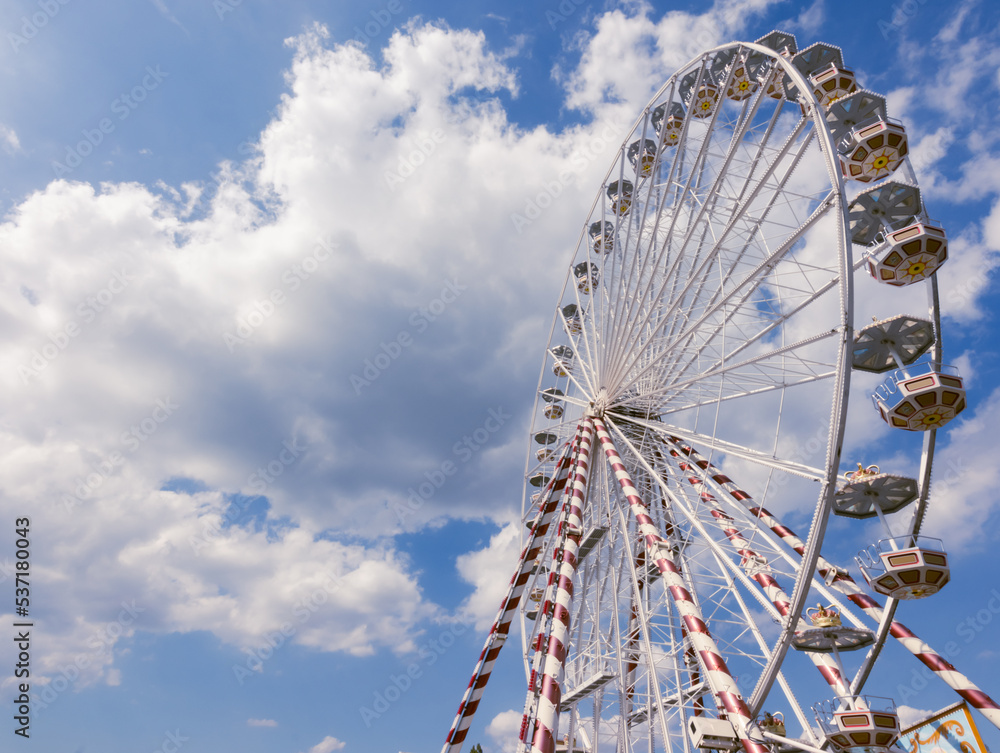 Ferris wheel in the city,a close-up view from the bottom against the blue sky.on the left there is a place for the inscription