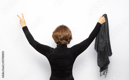 An Iranian female protester holds a hijab in her hand and shows a sign of victory.