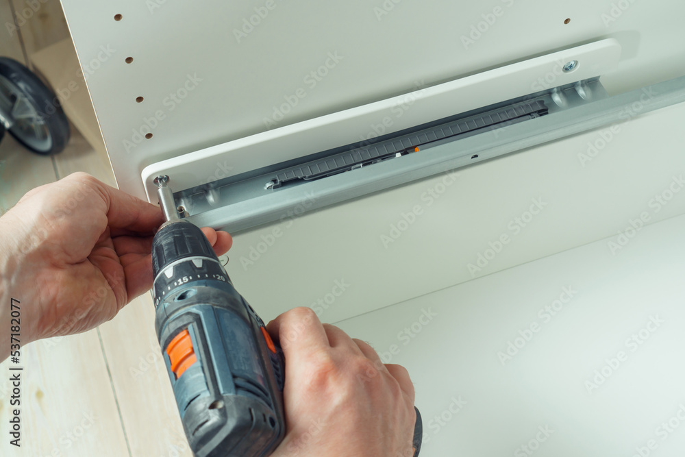 custom made wallpaper toronto digitalMale hands hold cordless electric screwdriver, screw to fix rail, assembling drawer of white dresser or wardrobe. Self-assembly of furniture at home, DIY, furniture repair and rearrangement