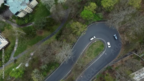 Aerial drone view of serpentine or curvy road with driving cars passing by, top down rotating shot photo