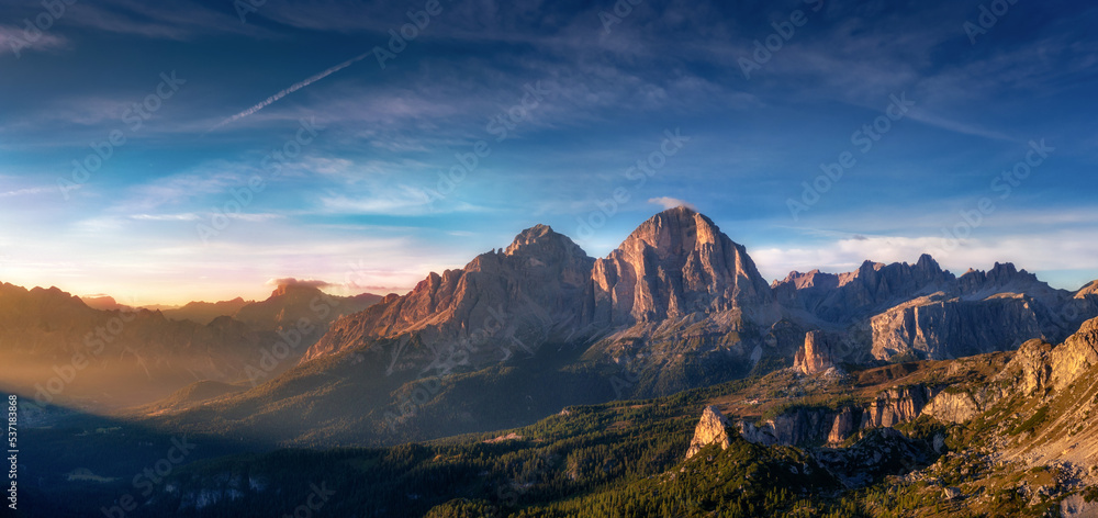 Beautiful mountain landscape with rays of the sun, blue sky with clouds and rocks at dawn. Tre Cime park in Dolomites, Italy. Italian alps
