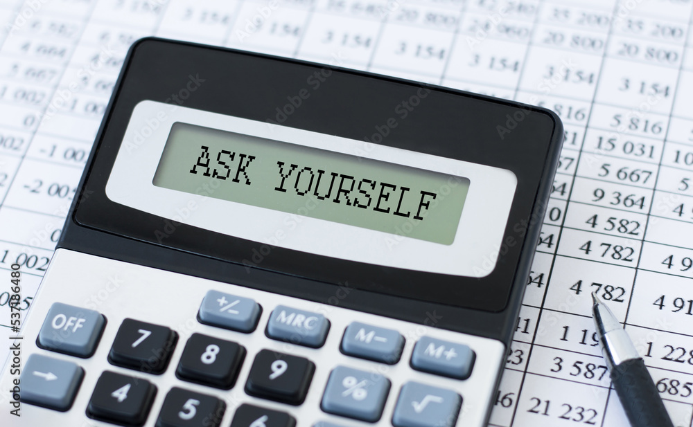 Ask YOURSELF inscription on the screen of the calculator on the table with documents, business concept Ask YOURSELF inscription on the screen of the calculator on the table with documents, business concept