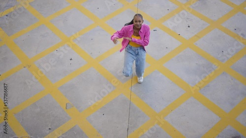 Cinematic footage of a professional hip hop female dancer outddor . Teenager girl with fashionable clothes dancing in a colored modern area of the city