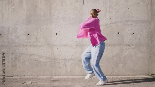 Cinematic footage of a professional hip hop female dancer outddor . Teenager girl with fashionable clothes dancing in a colored modern area of the city
