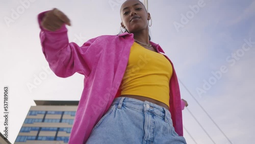 Cinematic footage of a professional hip hop female dancer outddor . Teenager girl with fashionable clothes dancing in a colored modern area of the city