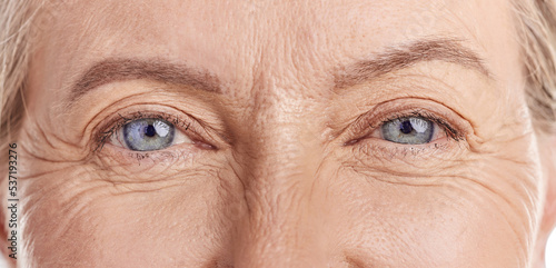 Closeup portrait of a beautiful older woman's blue eyes. Healthy and natural mature woman with deep lines and crows feet, Feeling radiant and fresh while doing her daily beauty routine in a studio