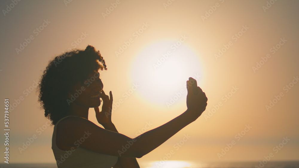 Woman taking self photo on smartphone at sunrise closeup. Girl posing for selfie