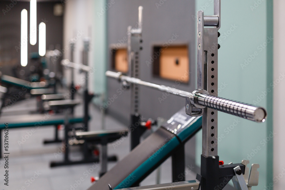 Fototapeta premium Close up of empty barbell bar without plates on rack in gym club.