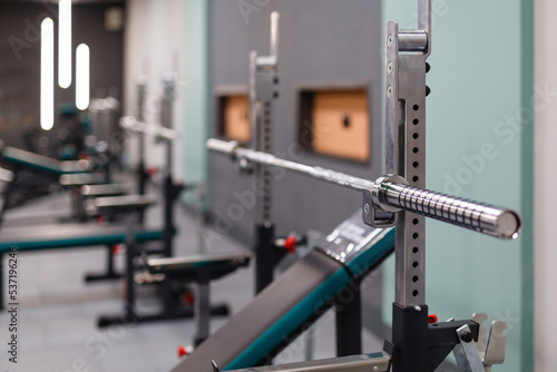 Close up of empty barbell bar without plates on rack in gym club.