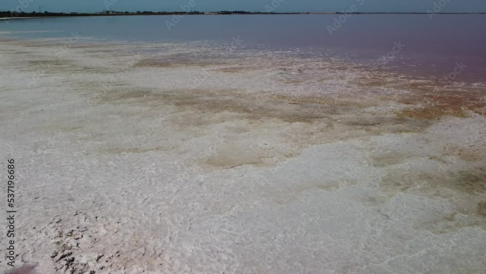 Woman in flying dress on pink salt lake. Salt production facilities saline evaporation pond fields in the salty lake. Woman in flying dress on pink salt lake. Salt production facilities saline evaporation pond fields in the salty lake.