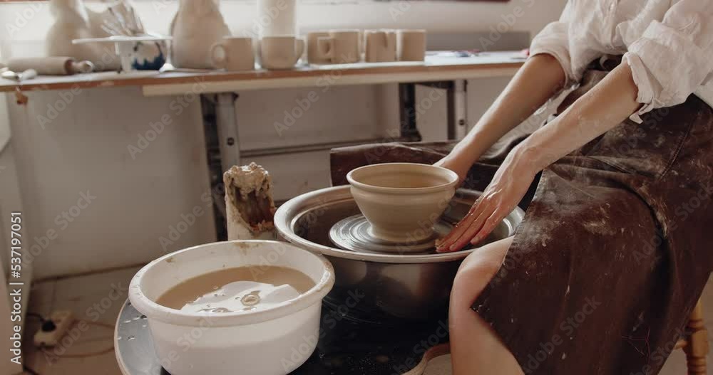 Woman sculptor making beautiful ware on throwing wheel in pottery workshop Woman sculptor making beautiful ware on throwing wheel in pottery workshop