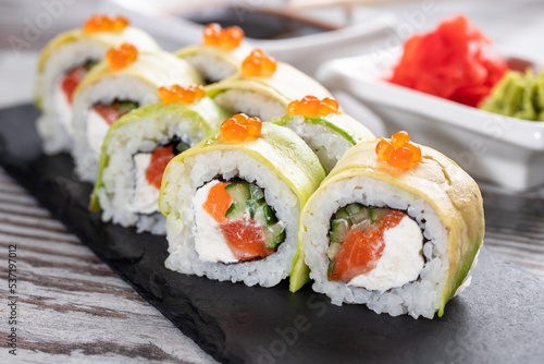 Close up of delicious pieces of sushi covered with fresh slices of avocado and red caviar.