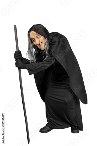 Old witch in a cloak standing with a stick
