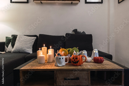 mesa llena de velas y decoraciones con dulces y tazas para halloween