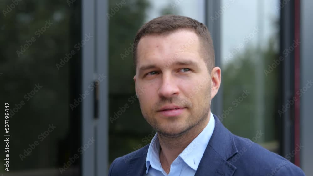 Close up of handsome young confident man in suit walking outdoors in city looking around. Caucasian successful businessman walks in street. Urban style, business concept. Close up of handsome young confident man in suit walking outdoors in city looking around. Caucasian successful businessman walks in street. Urban style, business concept.
