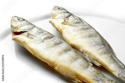 Smoked sea fish in a white plate on a white background. Close-up, selective focus.