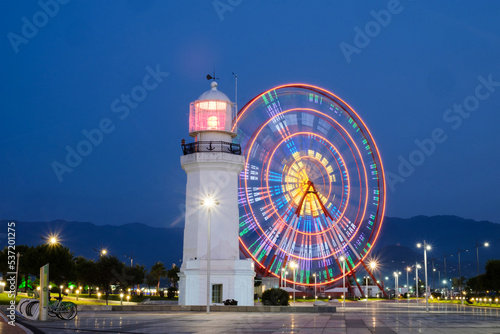 Ferris wheel and lighthouse at the illuminated area at night