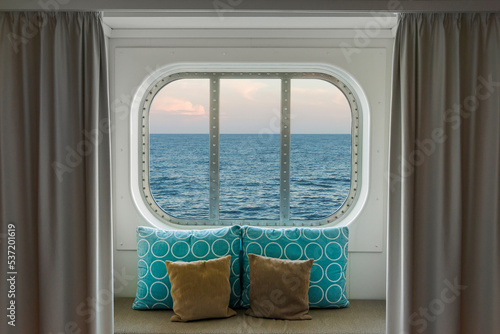 Blick durch das Kabinenfenster eines Kreuzfahrtschiffs bei Abendstimmung	
