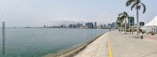 Panoramic view at the Luanda bay and Luanda marginal, pedestrian pathway with tropical palm trees, downtown lifestyle, Cabo Island, Port of Luanda and modern skyscrapers photo