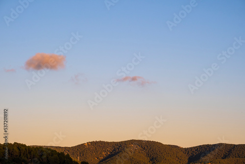 Landscape with forested mountain and a cloud in a clear sky