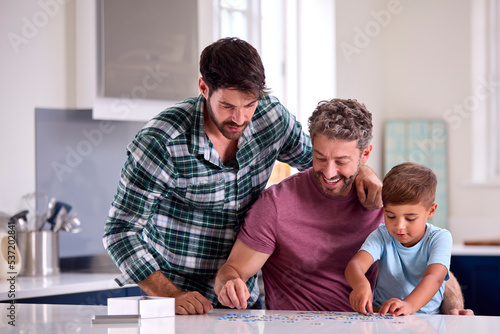 Same Sex Family With Two Dads And Son Doing Jigsaw Puzzle In Kitchen At Home