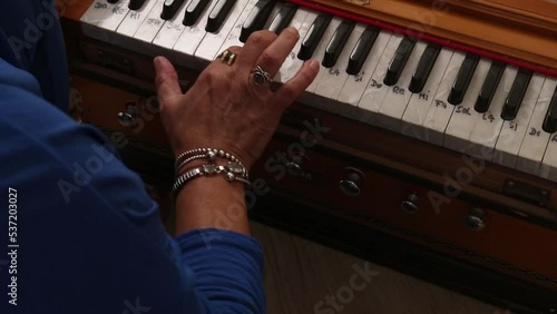 Detail shot of the yoga teacher playing a harmonium in a class in her own home. photo