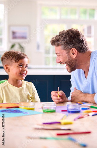 Mature Father At Home In Kitchen With Son Painting Picture Together