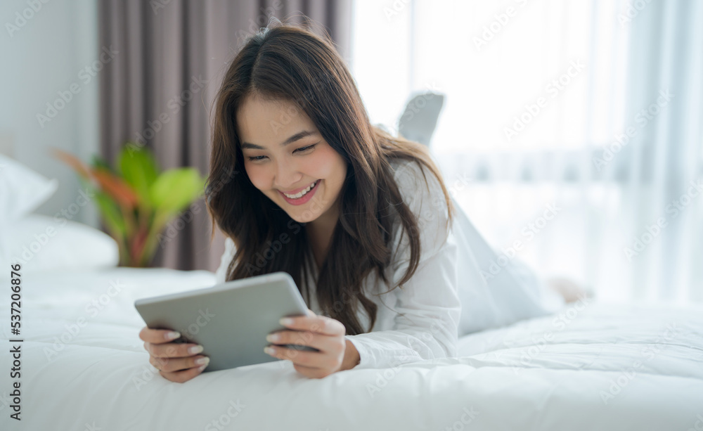 Girl lying in bed playing tablet computer in bedroom With a smiling face Girl lying in bed playing tablet computer in bedroom With a smiling face